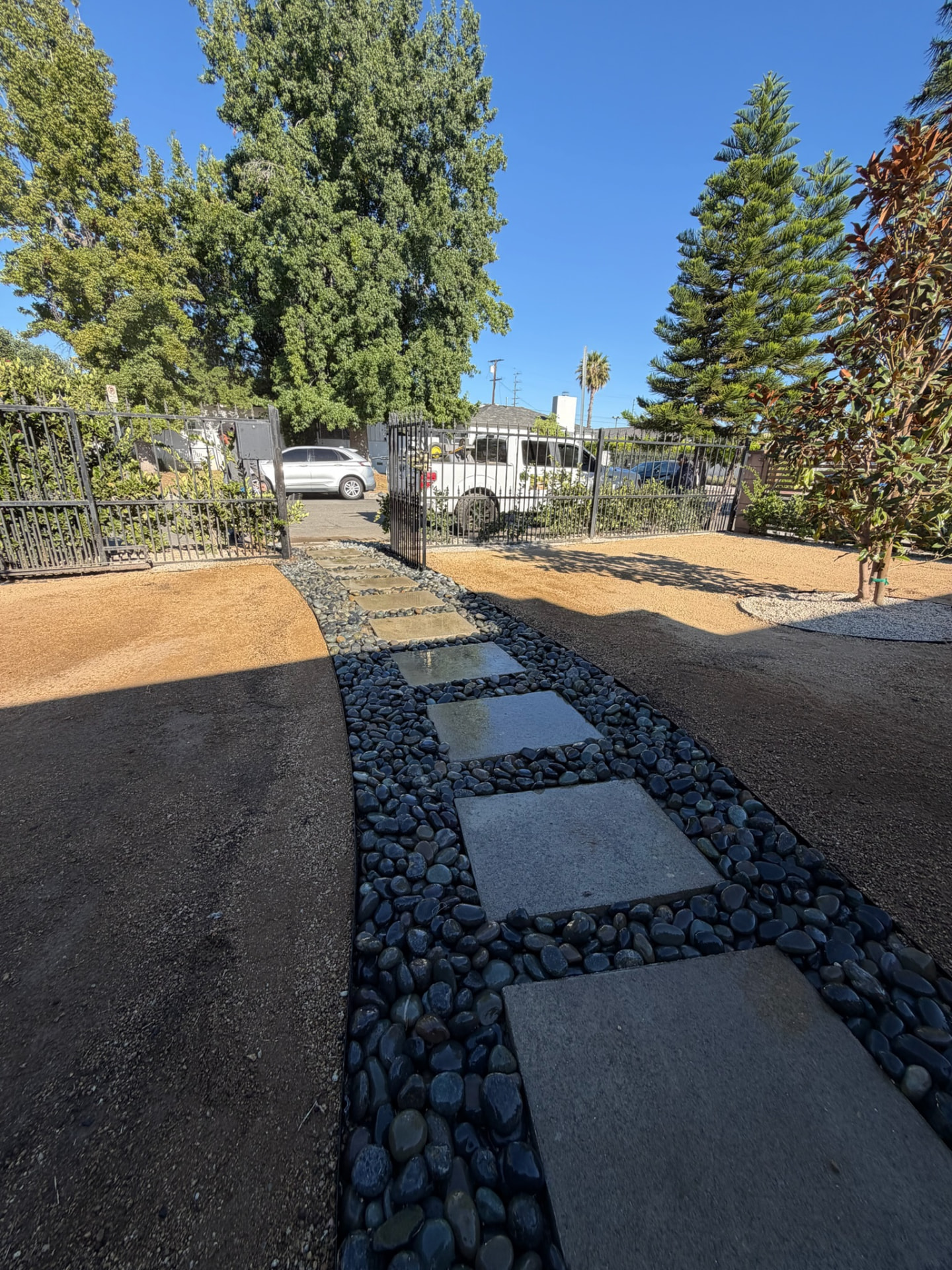 Modern stone stepping path set in black river rock with decomposed granite