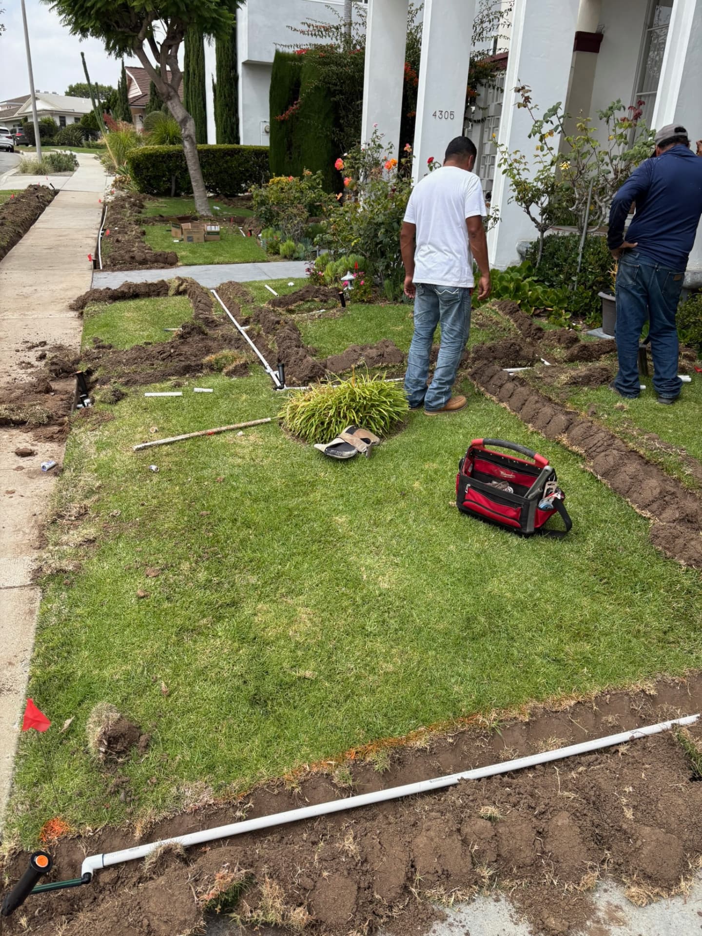 Crew trenching and installing an irrigation system in a front yard